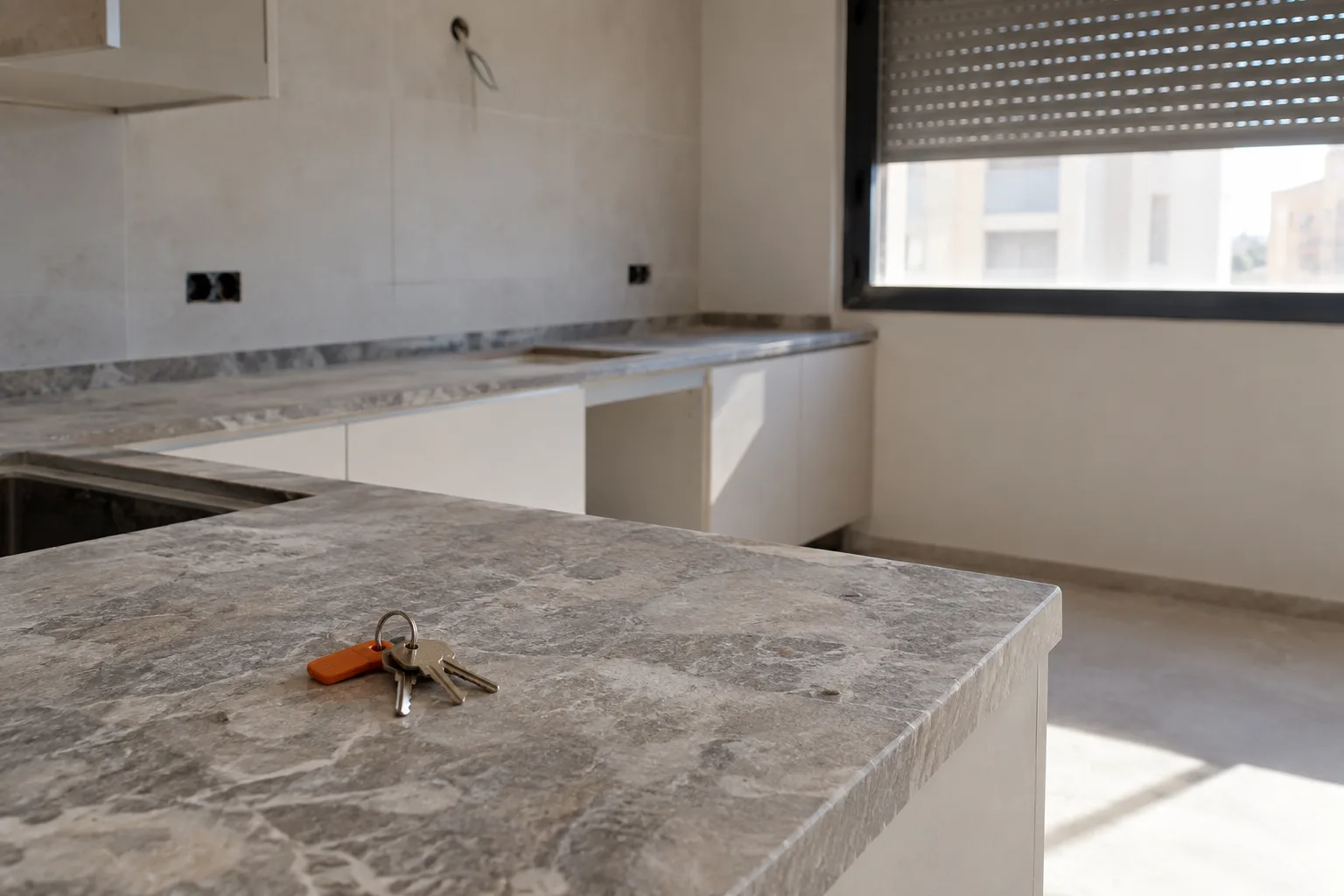 Llaves y documentos de compraventa sobre una mesa junto a una ventana con vistas al Mediterráneo